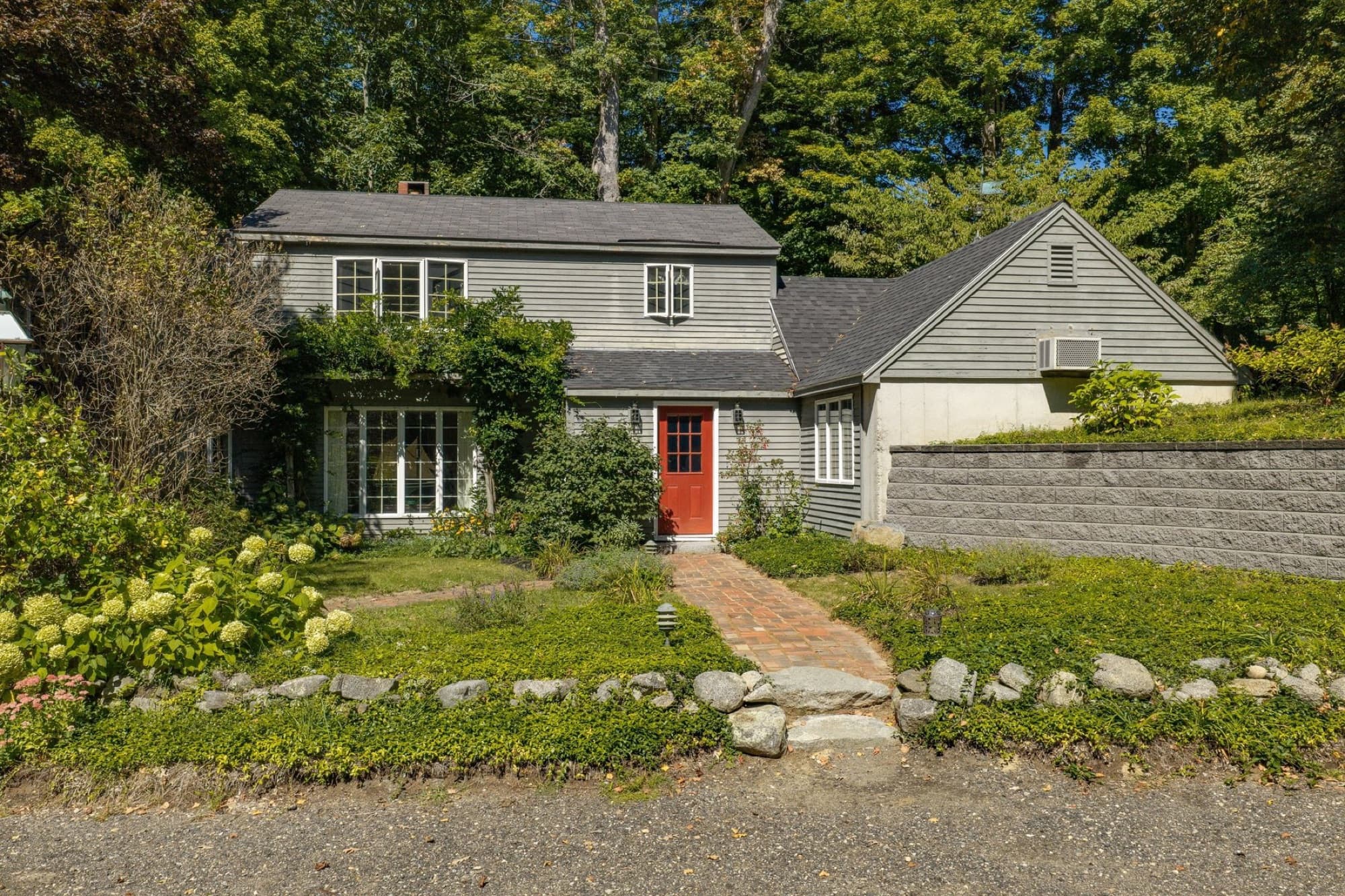 The house from the driveway, with the brick walk, the gardens, and the stone retaining wall