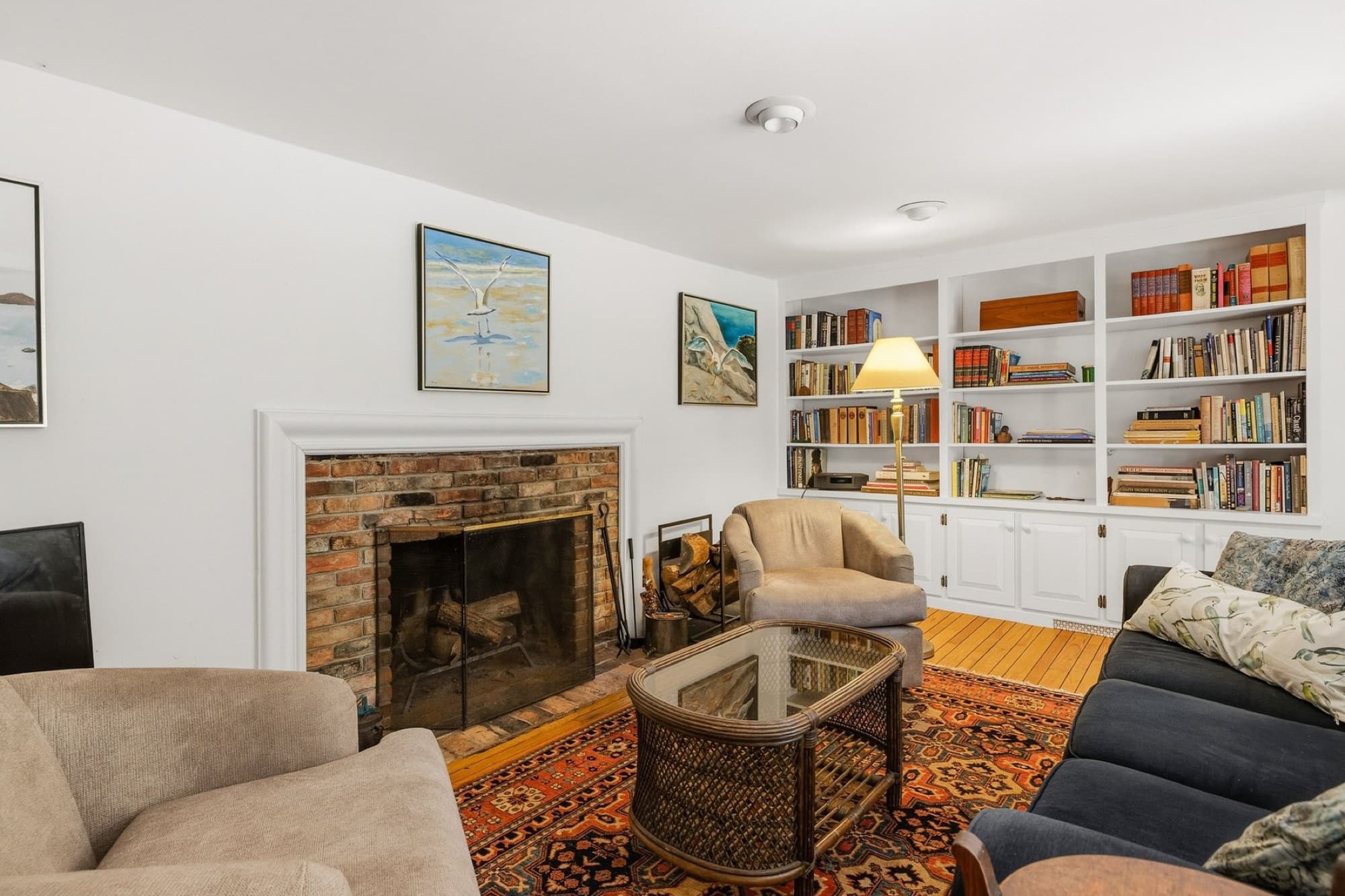 The living room's brick fireplace, lit, with built-in bookcases on either side