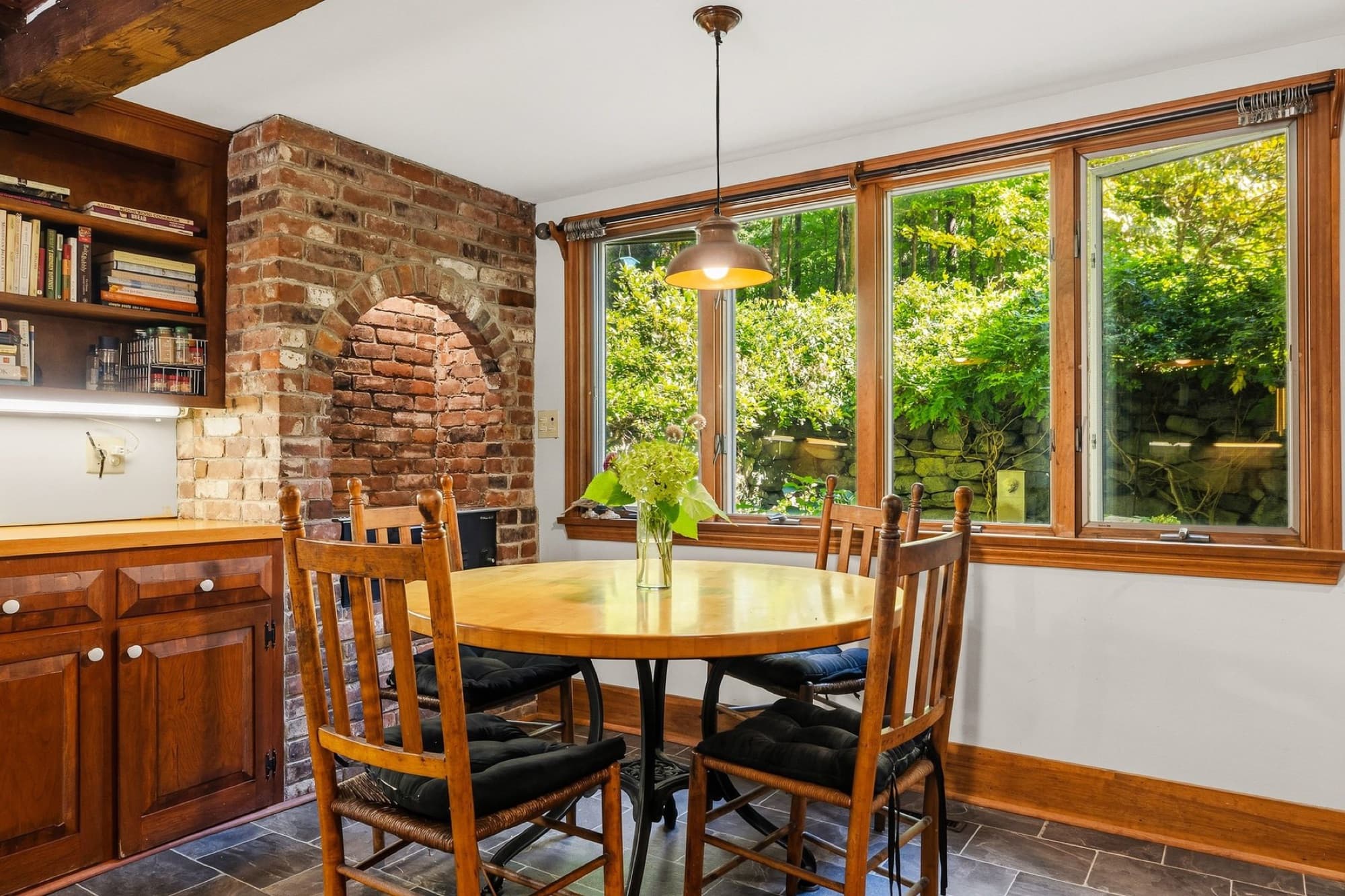 The kitchen's dining nook by the windows, with the brick chimney and its arched niche