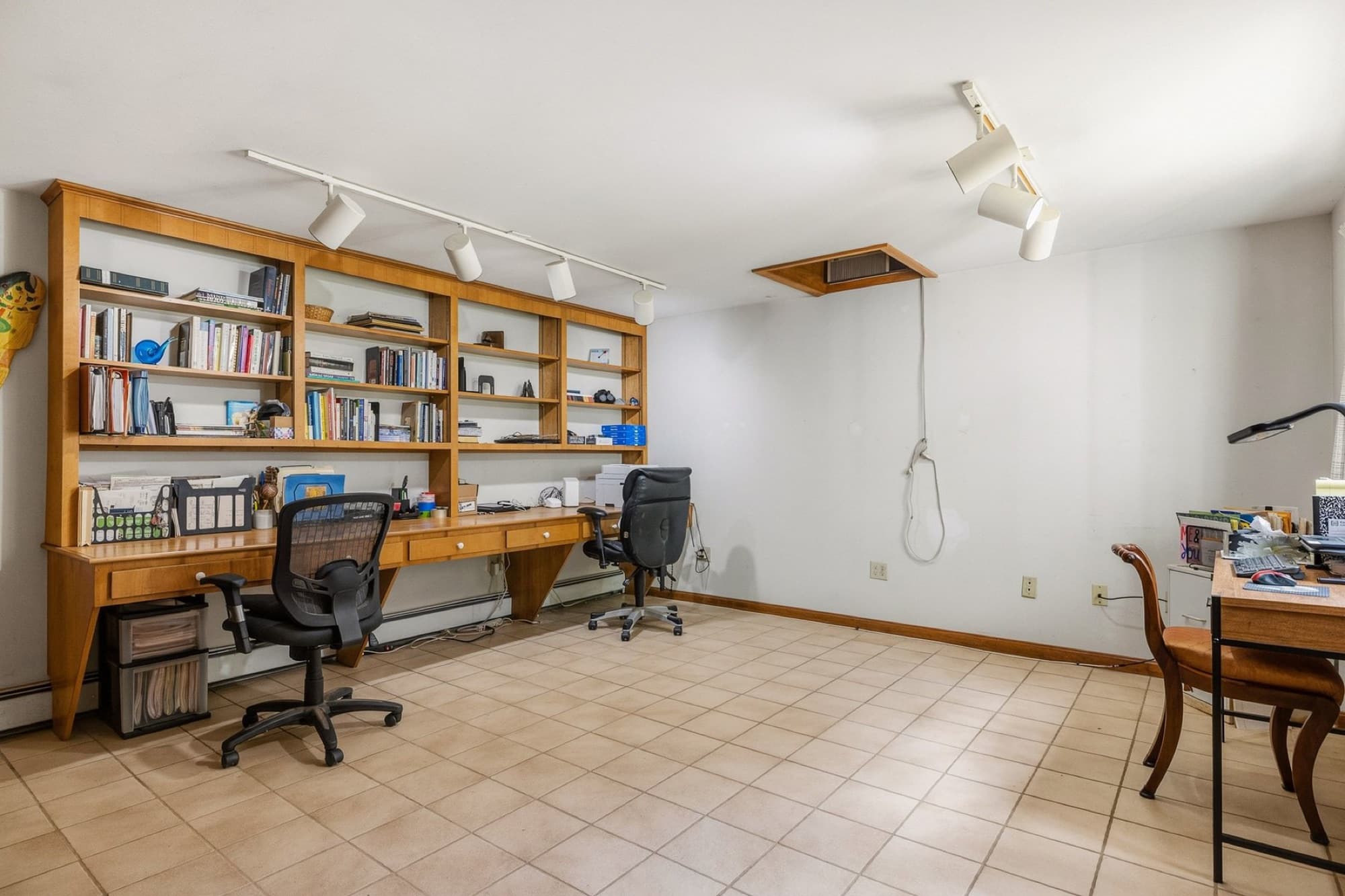 The first-floor bedroom, used as an office, with built-in shelving, 2 desks, and track lighting