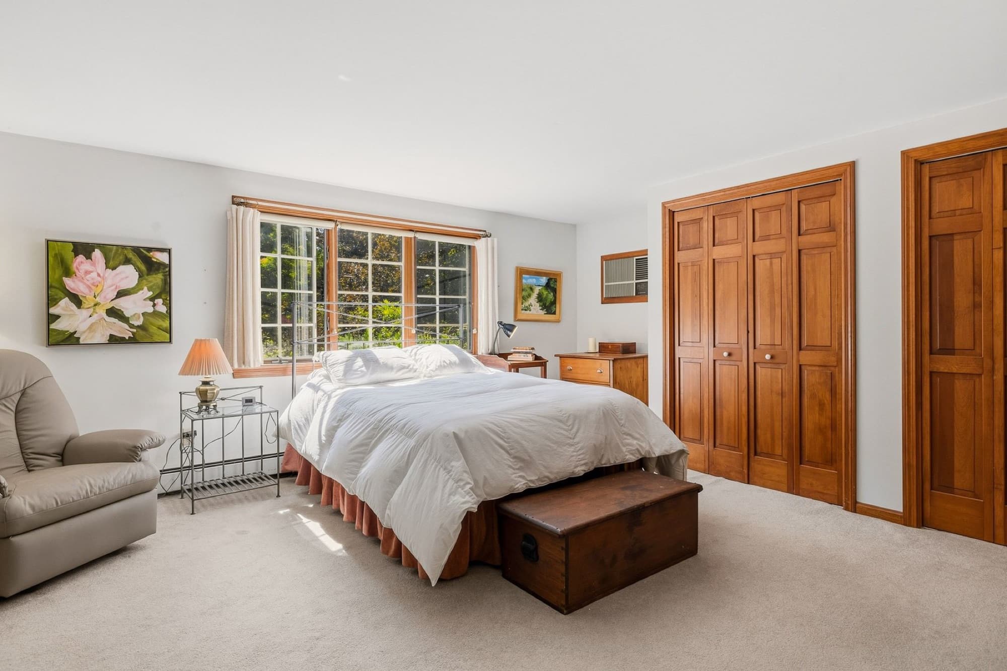 The primary bedroom with a wide window, carpet, and double closets